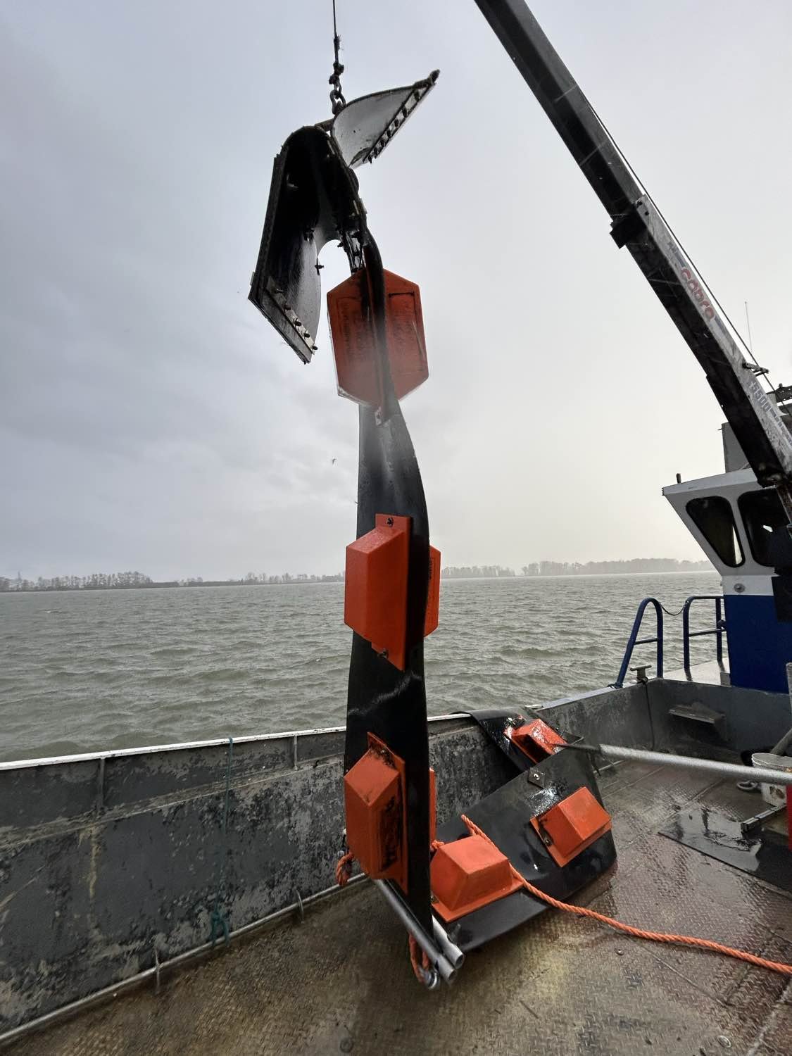 Damaged boom section lifted by crane for repair assessment