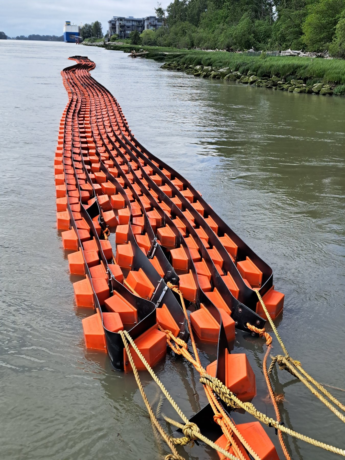 Assembled containment boom sections floating in river ready for towing