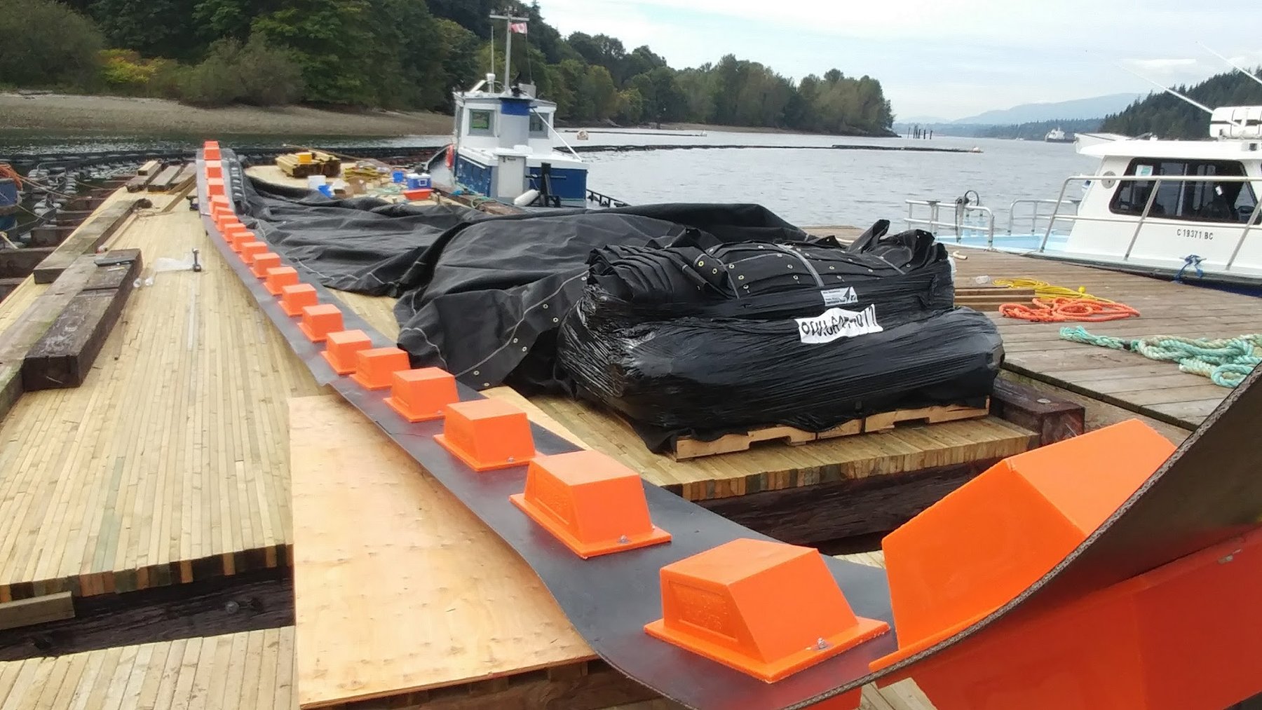 Containment boom section being assembled with floats and impermeable skirt