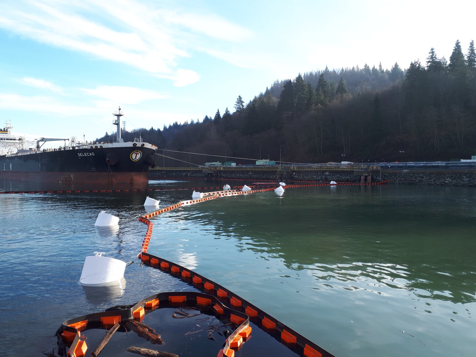 Construction containment boom deployed around moored tanker at fuel terminal